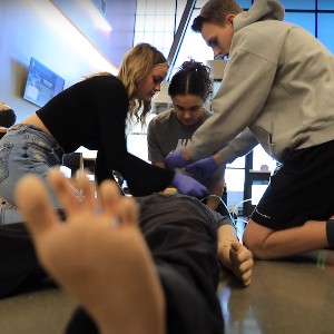 Students practice CPR on a training mannequin.